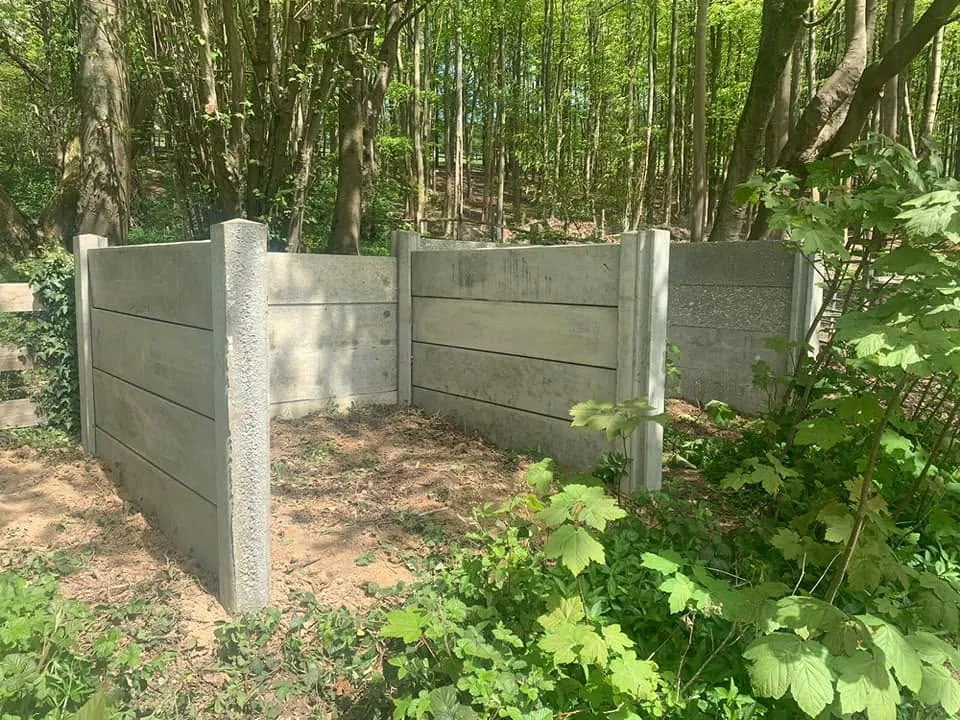 Two concrete compost bins built from concrete posts and gravel boards in woodland at Kemsing